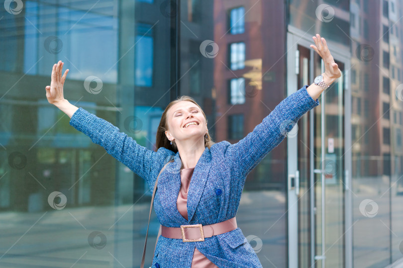 Скачать Счастливая деловая женщина показывает большие пальцы вверх, стоя на открытом воздухе напротив офиса фотосток Ozero