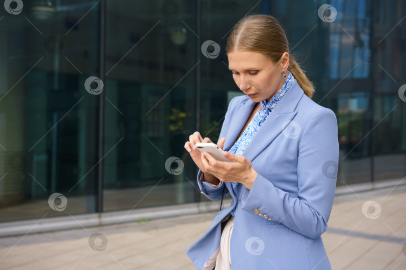 Скачать деловая женщина разговаривает по телефону на фоне офисного здания фотосток Ozero