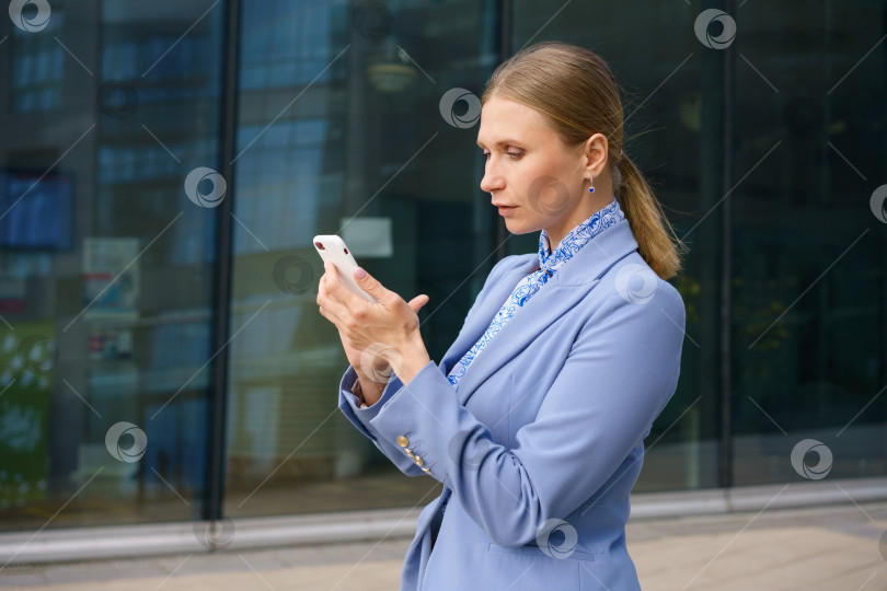 Скачать деловая женщина разговаривает по телефону на фоне офисного здания фотосток Ozero