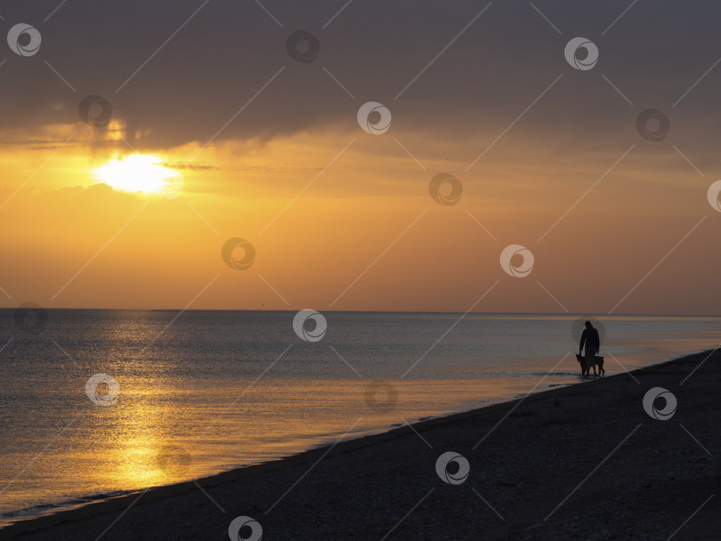 Скачать Потрясающий закат над морем, по берегу которого прогуливается девушка  фотосток Ozero