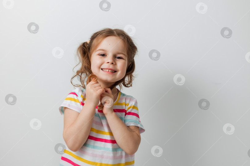 Скачать портрет милой девушки на светлом фоне, играющей со своими волосами фотосток Ozero