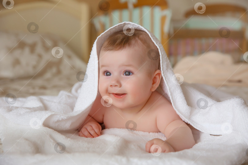 Скачать ребенок, накрытый полотенцем после купания, лежит на кровати в т фотосток Ozero