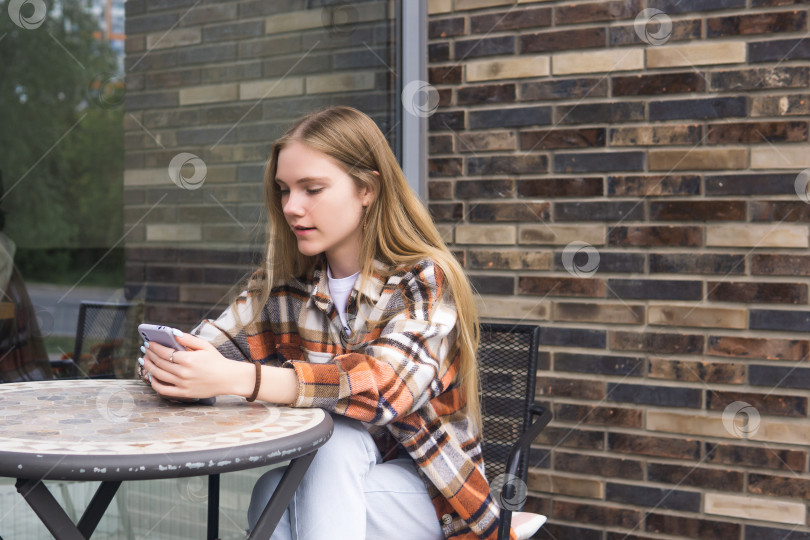 Скачать молодая женщина печатает что-то по телефону, сидя в офисе фотосток Ozero