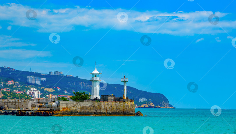 Скачать Ялтинский маяк в Крыму на берегу Черного моря в морском пассажирском порту на фоне красивых облаков. фотосток Ozero