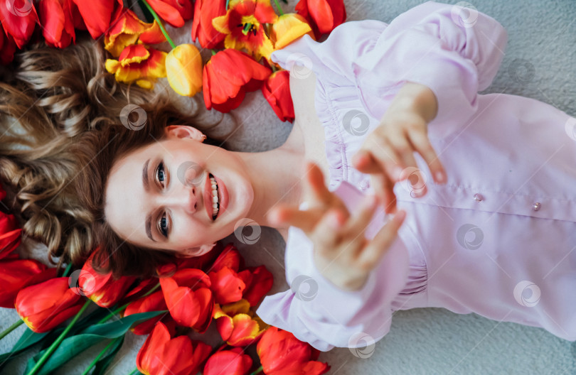 Скачать Молодая женщина лежит на полу среди красных тюльпанов. Концепция 8 марта, Дня святого Валентина. Весенний портрет женщины. фотосток Ozero
