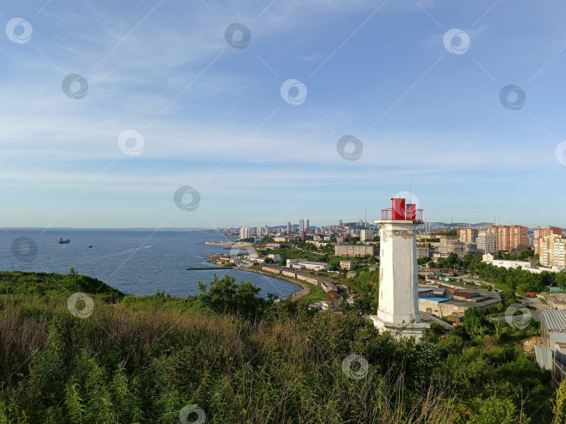 Скачать Маяк на фоне городского пейзажа в час летнего заката фотосток Ozero