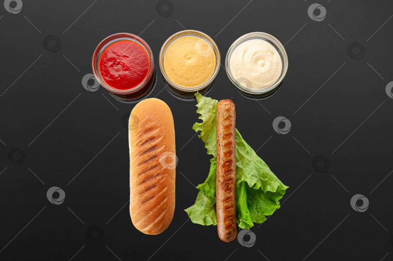 Скачать Ингредиенты для хот-догов. Булочка, колбаса-гриль, помидор и белый соус фотосток Ozero