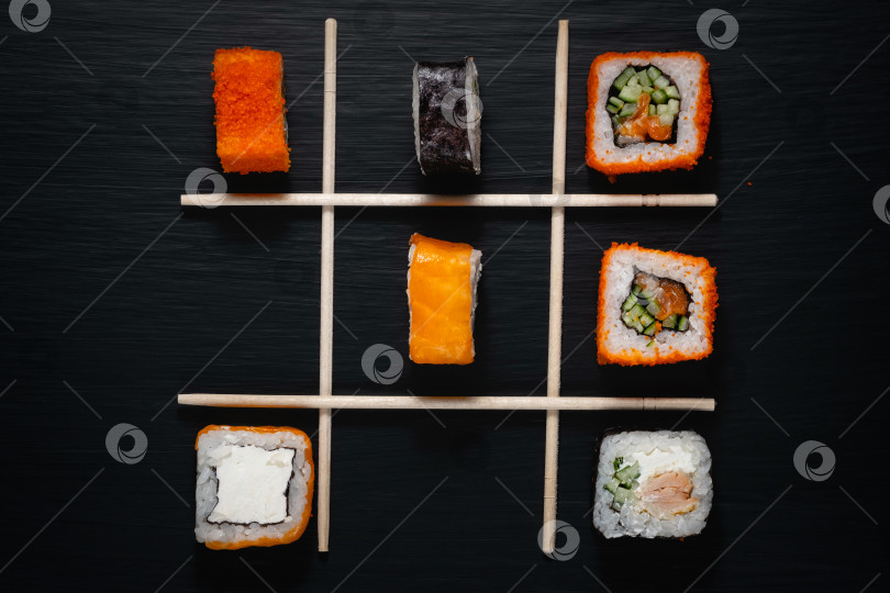 Скачать Различные виды суши и палочки для суши на черном деревянном столе. фотосток Ozero