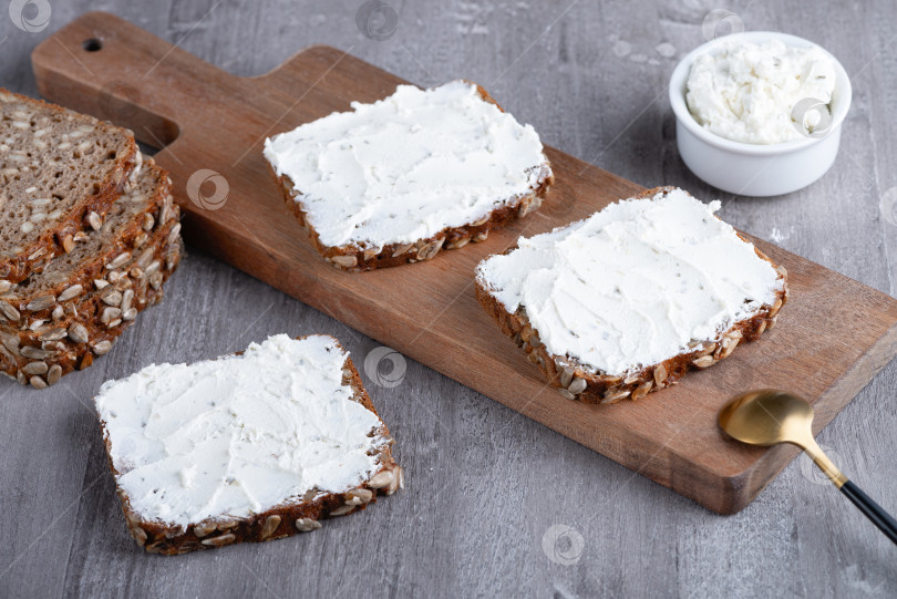 Скачать Ржаной хлеб со сливочным сыром на сером столе фотосток Ozero