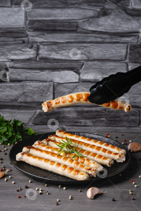 Скачать Свежие жареные куриные сосиски в тарелке на сером столе. Пустой c фотосток Ozero