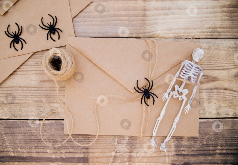 Скачать Конверт из крафт-бумаги и войлочные скелеты, пауки вокруг на деревянном фоне. Декор на Хэллоуин. фотосток Ozero