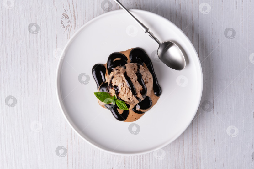 Скачать Шарик шоколадного мороженого и шоколадный соус, выложенный на белую бумагу фотосток Ozero