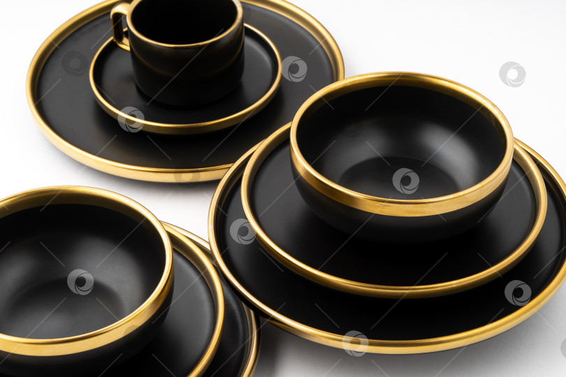 Скачать Набор черных и золотистых керамических тарелок и чашек на белой подставке фотосток Ozero