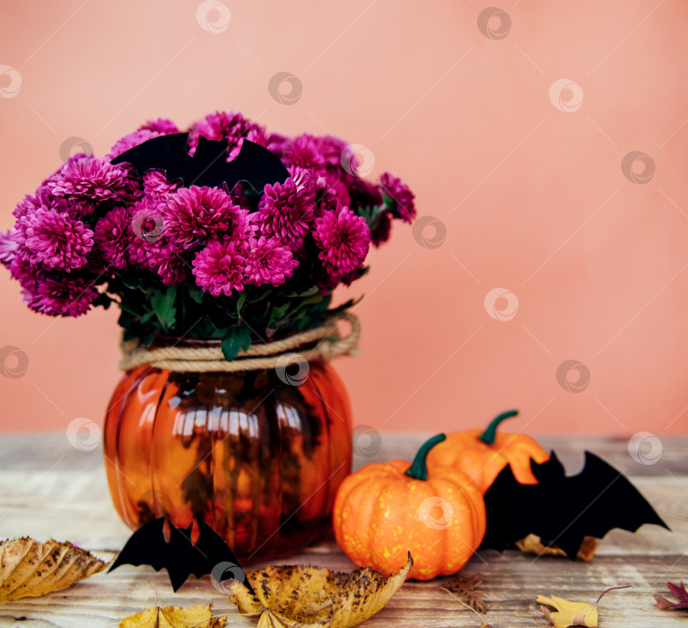 Скачать Две маленькие декоративные тыквы и ваза с хризантемами, бумажные летучие мыши на столе.Подготовка к празднику Хэллоуин. фотосток Ozero