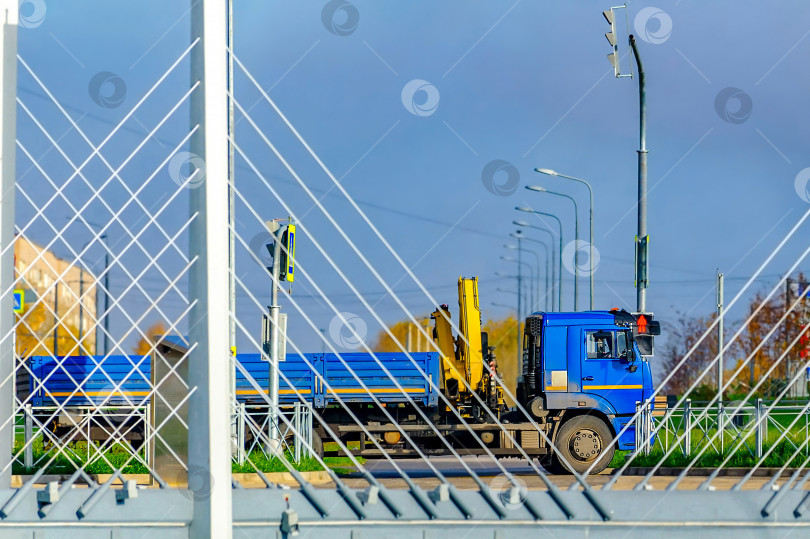 Скачать Синий грузовик в селективном фокусе с прицепом проезжает по вантовому мосту. фотосток Ozero