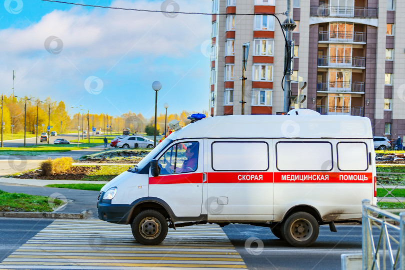 Скачать Череповец, Россия, 22 октября 2022 года, машина скорой помощи проезжает по пешеходному переходу на городской улице, чтобы спасти пациента. Надпись на машине "Скорая помощь". фотосток Ozero