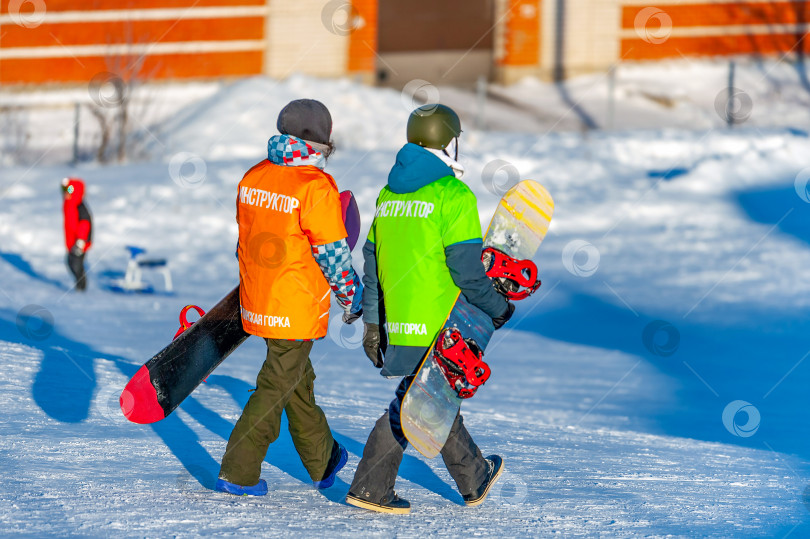 Скачать Россия, Череповец, 08 января 2023 года, два сноубордиста в selective focus прогуливаются со сноубордами в руках. Концепция спорта, здорового образа жизни. На куртке есть надпись: “инструктор, Грицинский холм”. фотосток Ozero