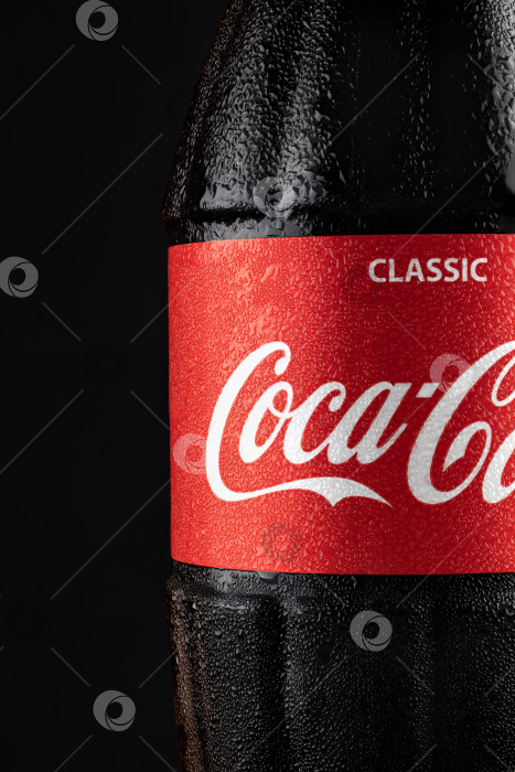 Скачать Батуми, Грузия - 10 июля 2023 года: Стеклянная бутылка ледяной кока-колы на черном фоне. Coca-Cola - самая популярная газировка в мире. фотосток Ozero