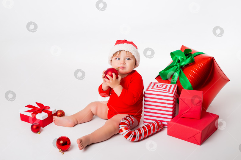 Скачать Милый малыш Санта с подарочными коробками улыбается на белом фоне. концепция Рождества. Пространство для текста фотосток Ozero