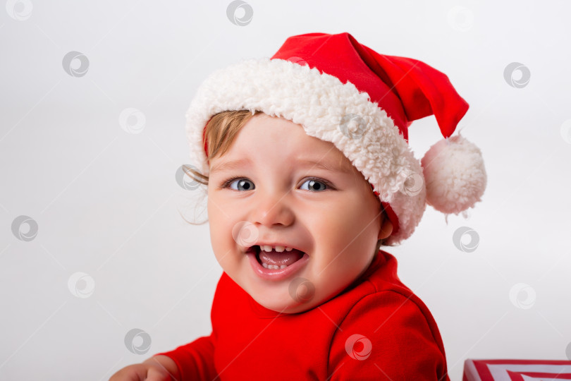 Скачать Милый малыш Санта с подарочными коробками улыбается на белом фоне. концепция Рождества. Пространство для текста фотосток Ozero