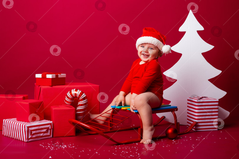 Скачать Милый малыш Санта сидит на санках с рождественскими подарками. Рождественская концепция, текстовое пространство фотосток Ozero