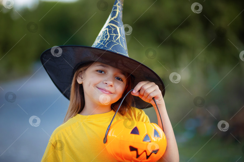 Скачать Портрет девушки в ведьминой шляпе с конфетницей в виде тыквы в руках фотосток Ozero