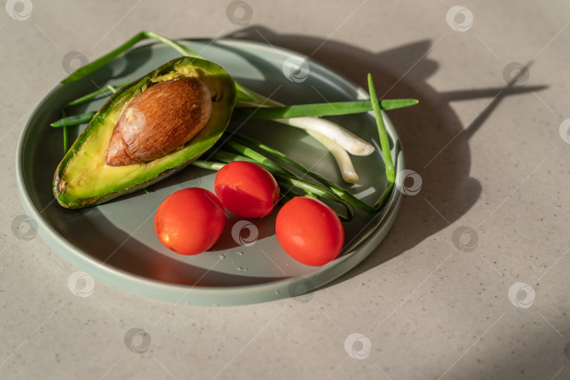 Скачать На тарелке свежие овощи, авокадо, помидоры черри и зелень. Полезный веганский завтрак. фотосток Ozero