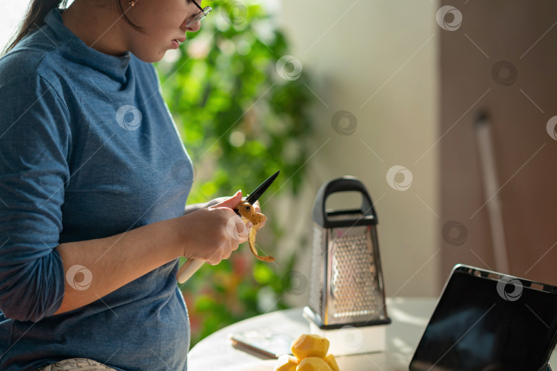 Скачать Крупный план женских рук, чистящих картофель над кухонным столом фотосток Ozero