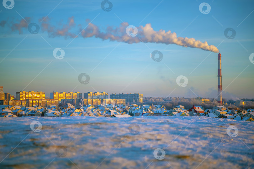 Скачать Городской пейзаж - вид на крыши жилых зданий, коттеджей в черте города. Холодным зимним вечером вид на город с вершины горы на закате.Солнечные блики на снегу в окнах. фотосток Ozero