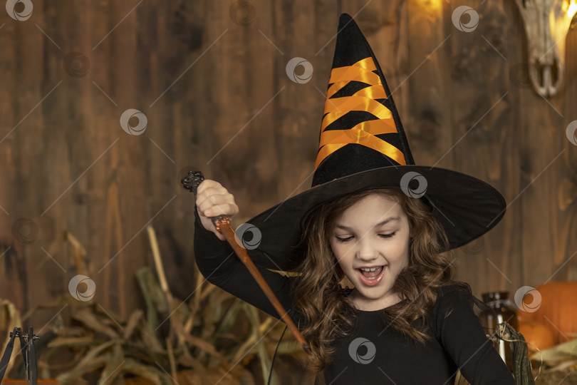 Скачать Милая маленькая девочка-ведьма позирует в декорациях Хэллоуина. Вечеринка в честь Хэллоуина. фотосток Ozero