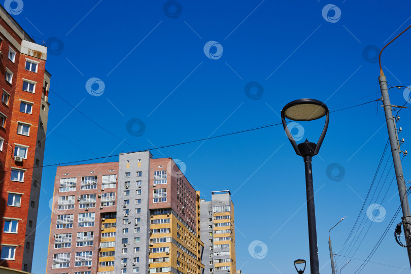Скачать освещение фонарных столбов и многоэтажных жилых зданий. Солнечный день. Голубое небо. фотосток Ozero