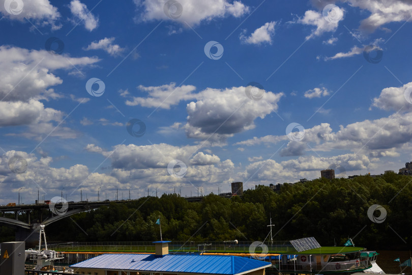 Скачать голубое небо с облаками, перекинутыми через речные деревья. фотосток Ozero