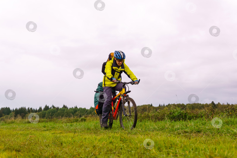 Скачать велосипедист смотрит на дорогу, проезжая по полю в фотосток Ozero