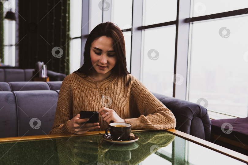 Скачать молодая женщина набирает номер по телефону, сидя в кафе фотосток Ozero