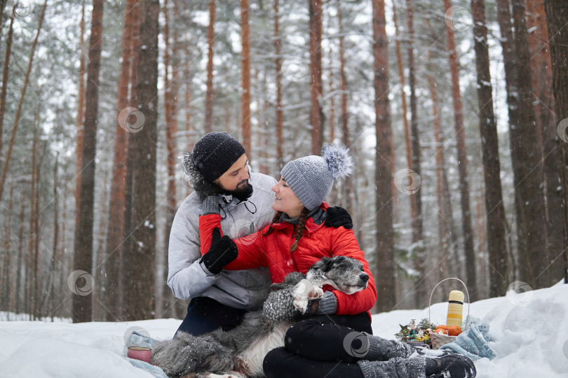 Скачать молодая пара с собакой устраивают пикник в заснеженном лесу фотосток Ozero
