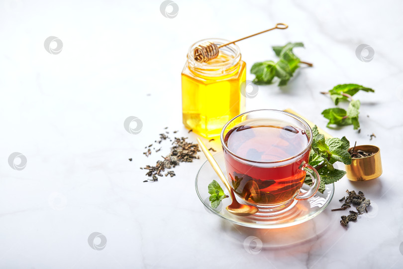 Скачать Черный чай в стеклянной прозрачной кружке с листьями мяты и медом. Успокаивающий и восстанавливающий чай, антистресс и релаксация фотосток Ozero