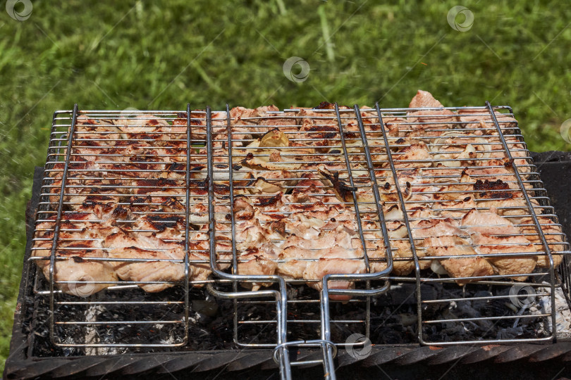 Скачать Мясо обжаривается над раскаленными углями в жаровне на решетке. фотосток Ozero