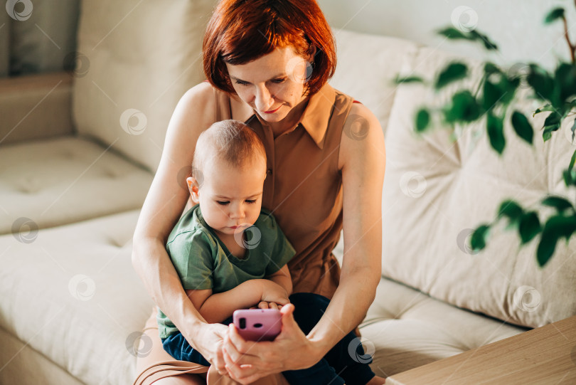 Скачать Мама с ребенком смотрят на смарт-мобильный телефон видео или рабочий текст фотосток Ozero