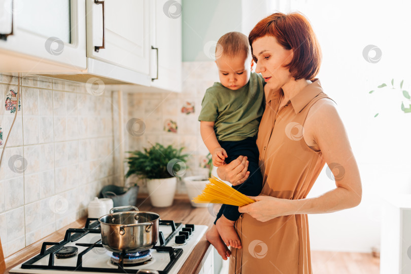 Скачать Счастливая мама со своим ребенком готовит на кухне. Уютный дом и рутинные обязанности фотосток Ozero