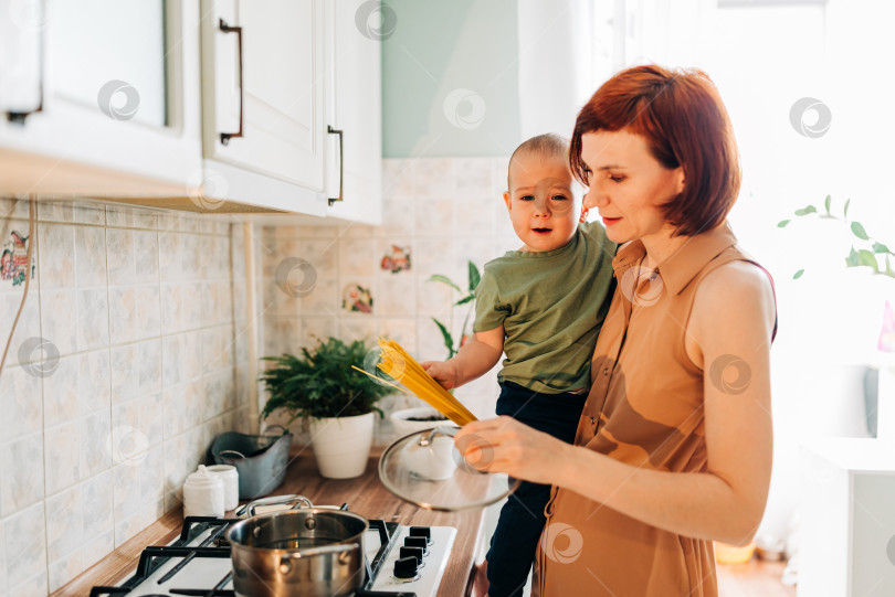 Скачать Счастливая мама со своим ребенком готовит на кухне. Уютный дом и рутинные обязанности фотосток Ozero