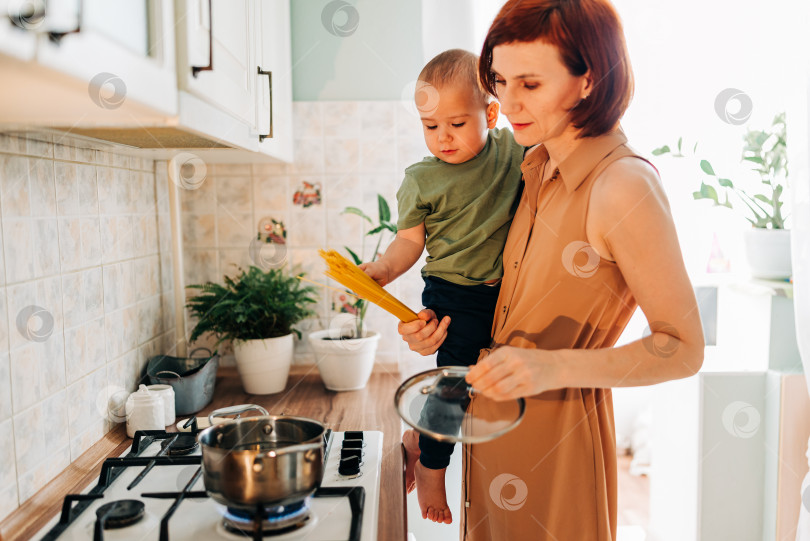 Скачать Счастливая мама со своим ребенком готовит на кухне. Уютный дом и рутинные обязанности фотосток Ozero