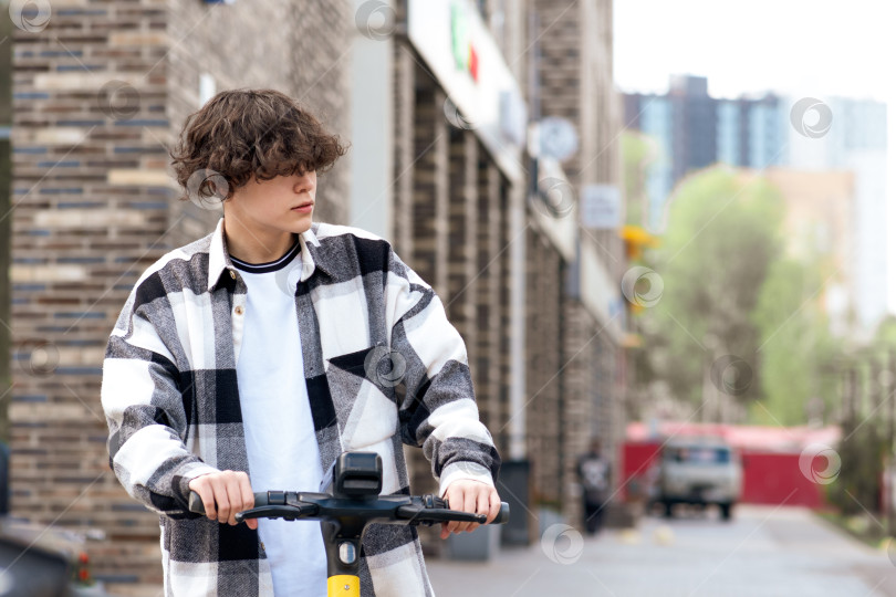 Скачать молодой человек на электрическом скутере едет по улице фотосток Ozero