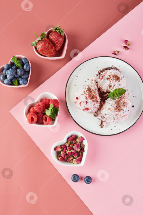 Скачать Тарелка с шариками мороженого с ягодами и маленькие тарелочки в виде сердечек со свежими ягодами, клубникой, малиной, черникой на розовом фоне. Вид сверху фотосток Ozero