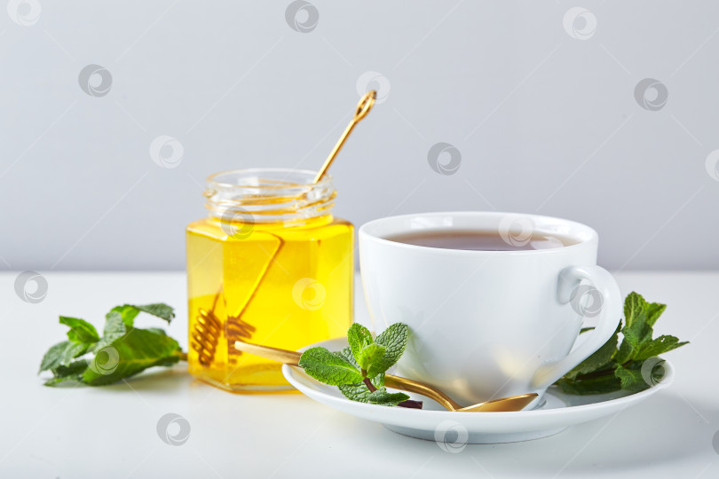 Скачать Черный чай в белой чашке с листьями мяты и медом. Успокаивающий и восстанавливающий чай, антистресс и релаксация фотосток Ozero