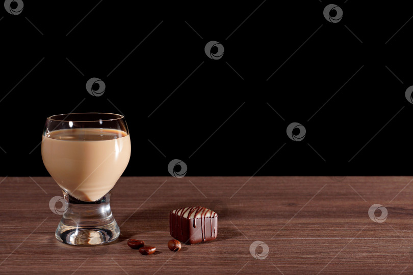 Скачать Бокал с ликером, конфетами и кофейными зернами на черном фоне. фотосток Ozero
