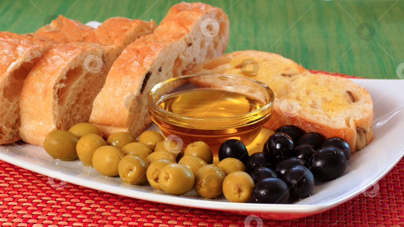 Скачать Зеленые и черные оливки, миска с оливковым маслом и домашний хлеб фотосток Ozero