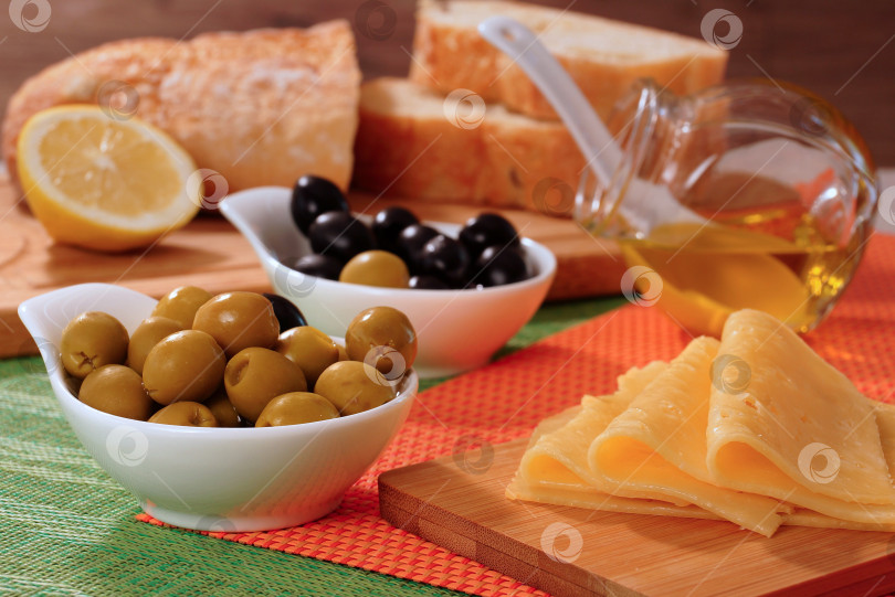 Скачать Черные и зеленые оливки, сыр, бутылочка с маслом и домашний хлеб фотосток Ozero
