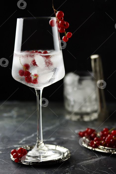 Скачать Напиток из красной смородины со льдом. Свежий фруктовый коктейль со льдом в бокале для вина, освежающий летний напиток из ягод красной смородины на фоне каменного бетона, вид спереди, место для копирования. Вода из красной смородины крупным планом фотосток Ozero