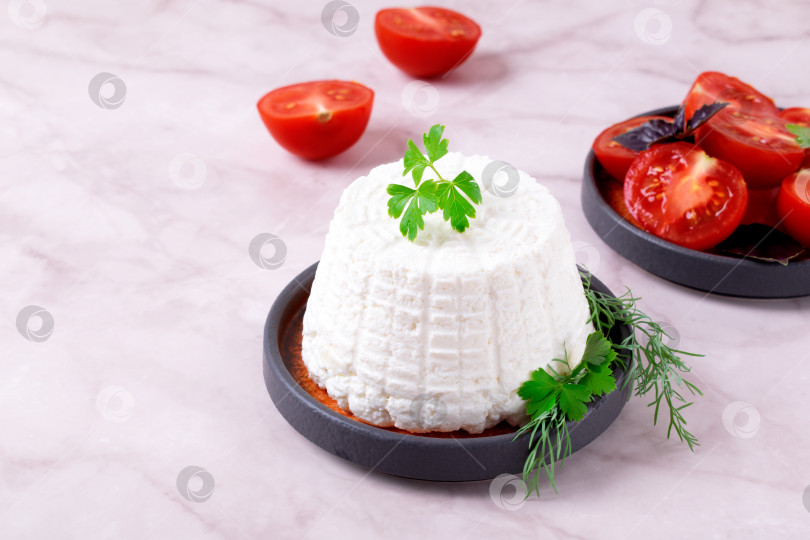 Скачать Свежий сыр рикотта, посыпанный петрушкой, подается с помидорами черри на белом столе. фотосток Ozero