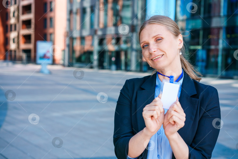 Скачать Успешная деловая женщина в синем костюме и рубашке держит в руке бейдж фотосток Ozero